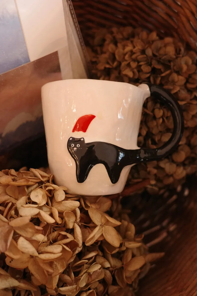 Christmas black cat mug nestled in dried hydrangeas in a basket