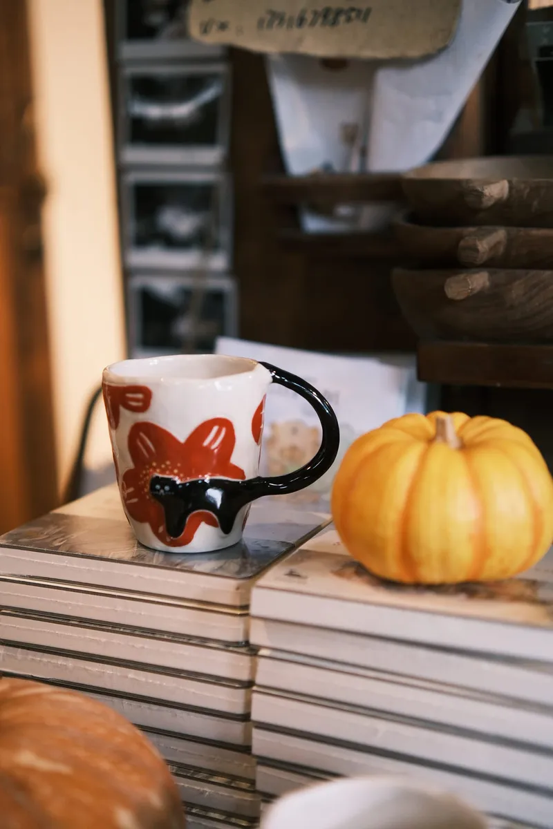 Red flowers mug on a stack of books with a small pumpkin