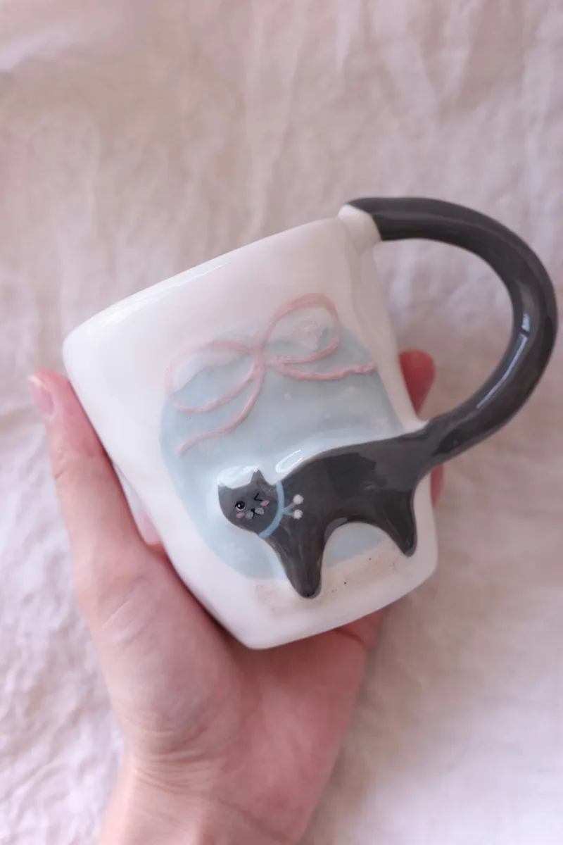 Blue-grey cat mug held in one hand