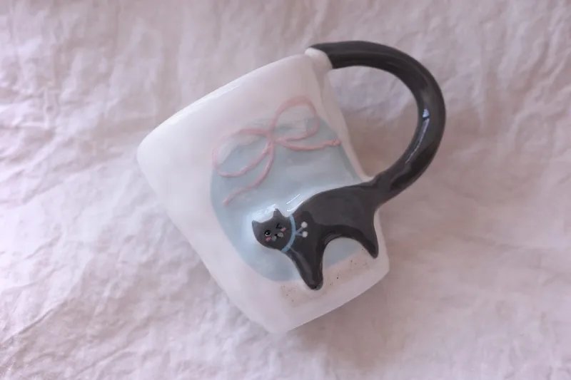 Blue-grey cat mug lying on white linen