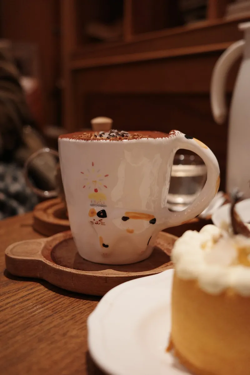 Calico birthday mug with cocoa on a cafe table
