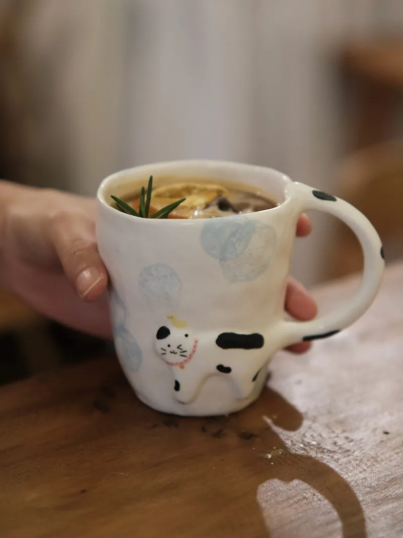 Cow cat mug with a slice of lemon held in one hand