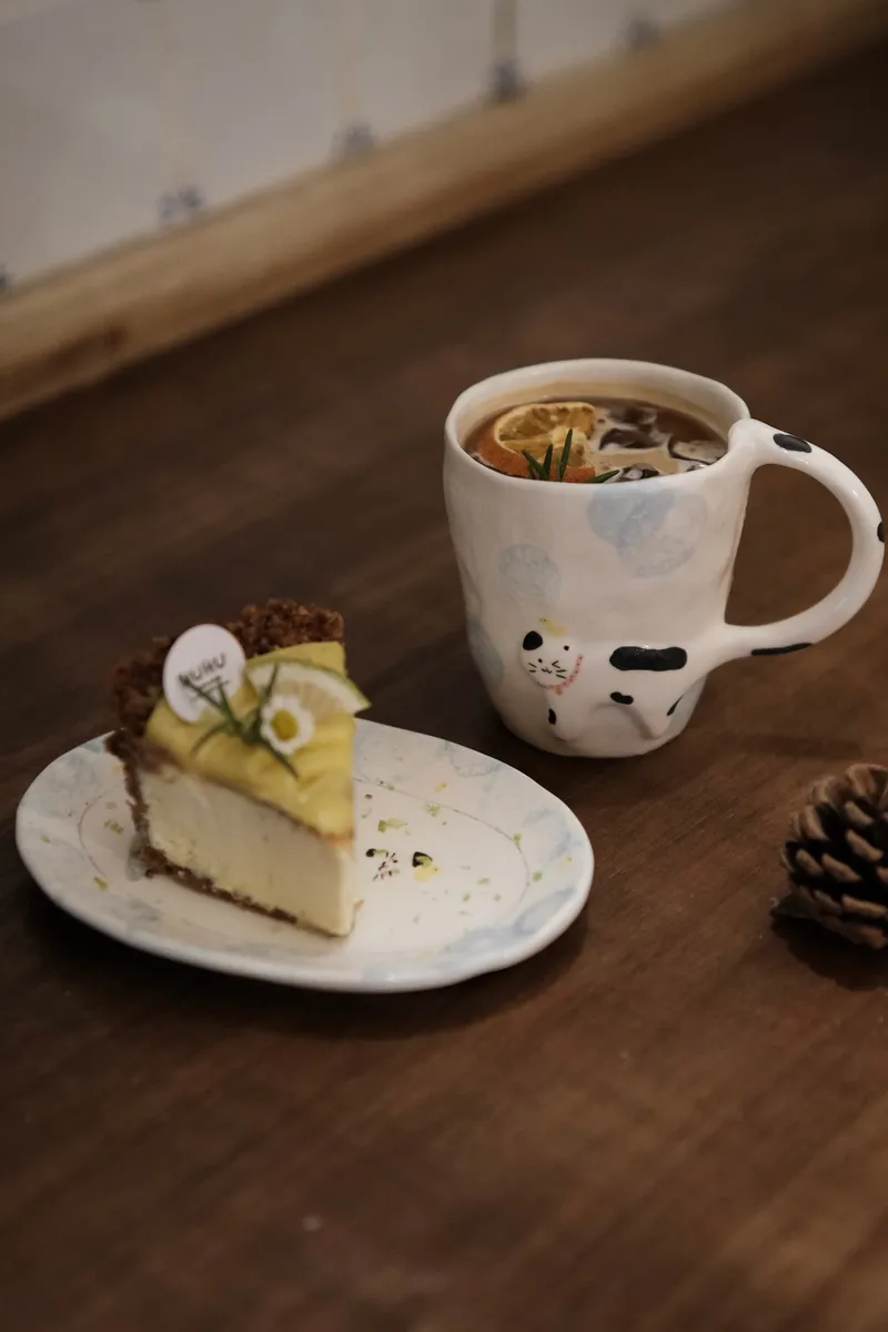 Cow cat mug with tea next to a slice of cake