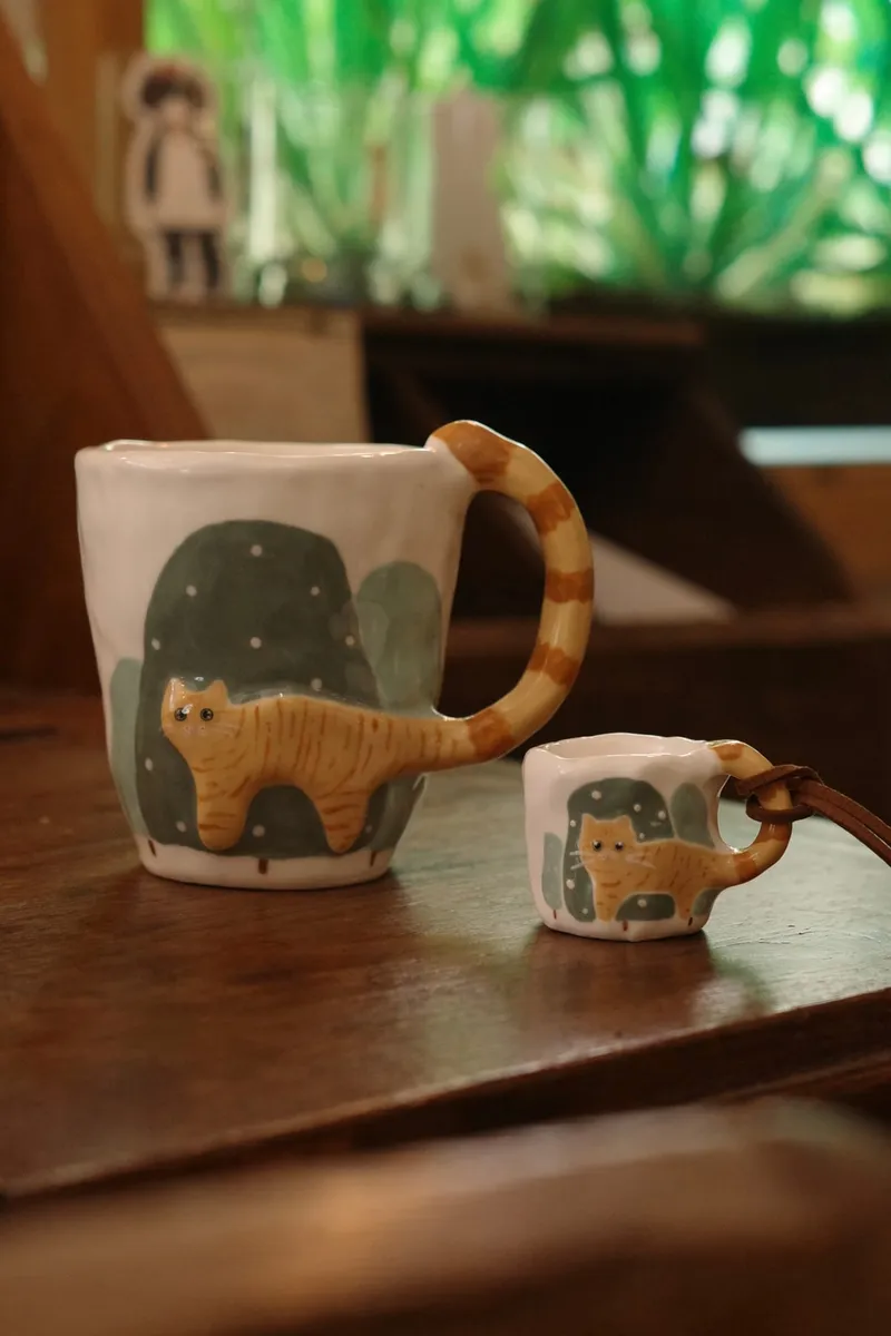 Orange cat mug and a small companion mug on a wooden table