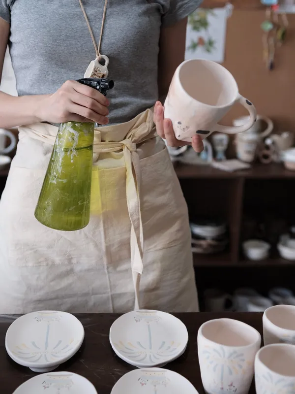 Glazing a cat mug over a bucket in the studio