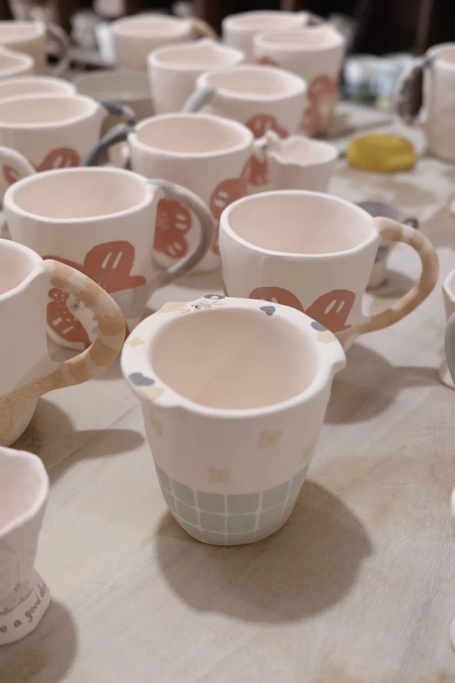 Hand holding a mug with a pencilled cat design before painting