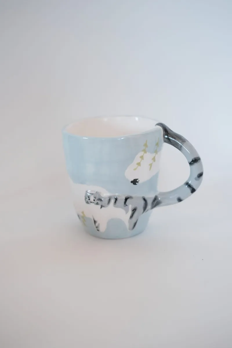 Tabby cat mug with a blue sky background on a white cloth