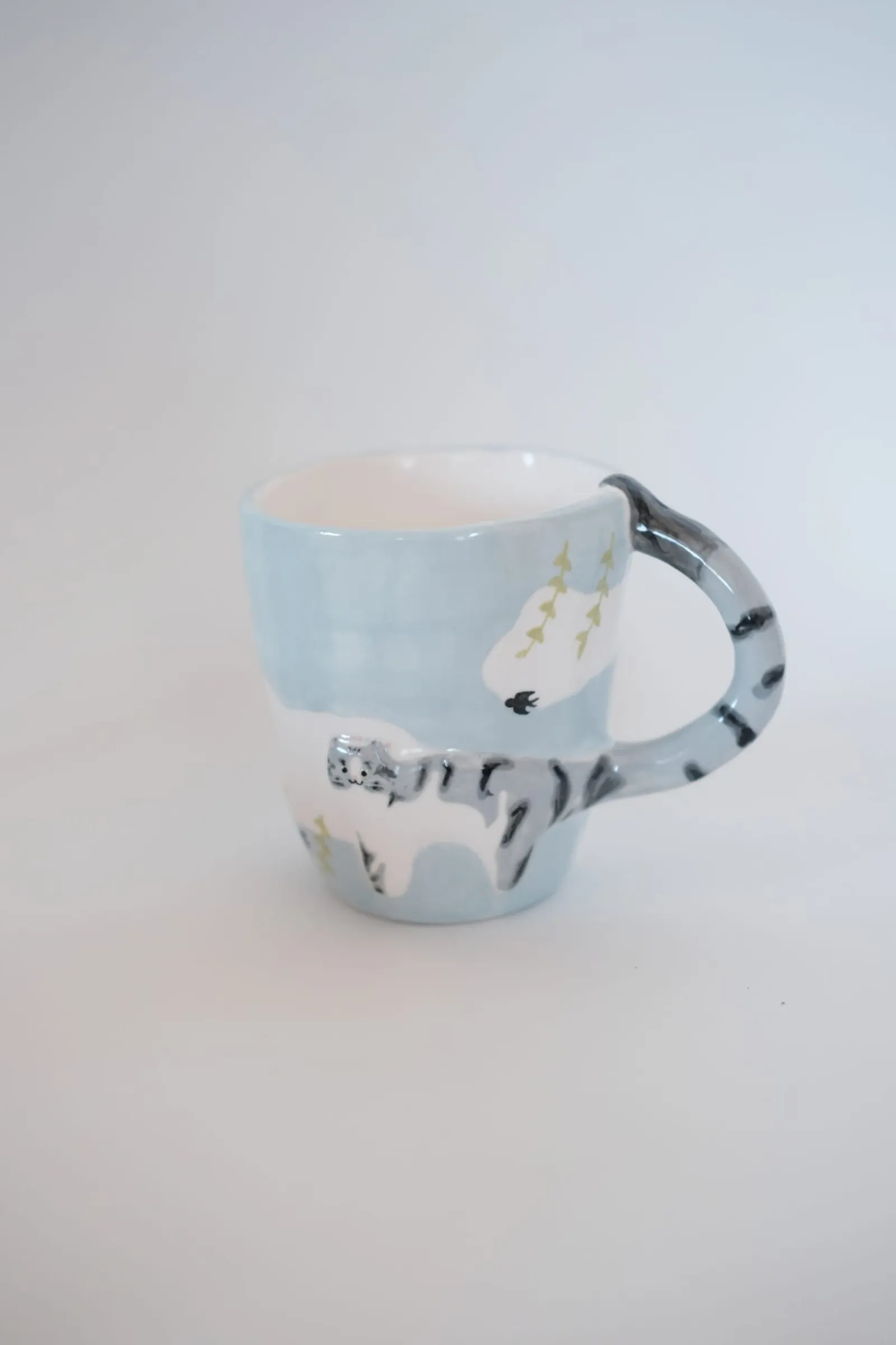 Tabby cat mug with a blue sky background on a white cloth